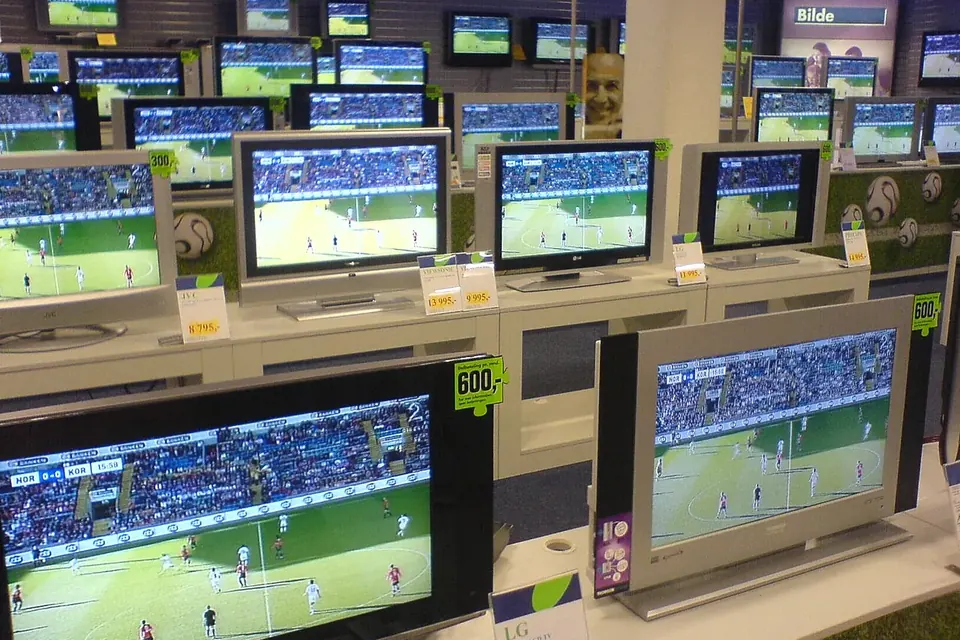 Rows of flat-screen televisions on display shelves in a shop, all showing the same football match