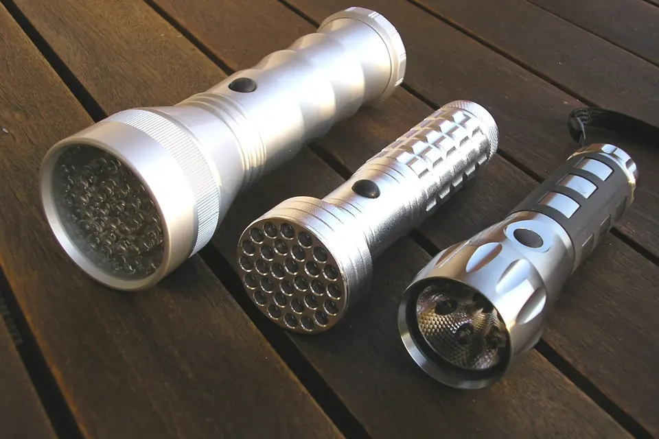 Three aluminium LED torches of different sizes lying on a wooden table