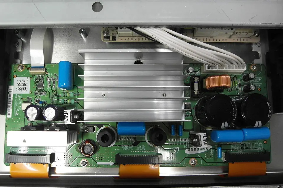 A plasma TV sustain board with a large aluminium heatsink, capacitors and orange flex connectors along its lower edge