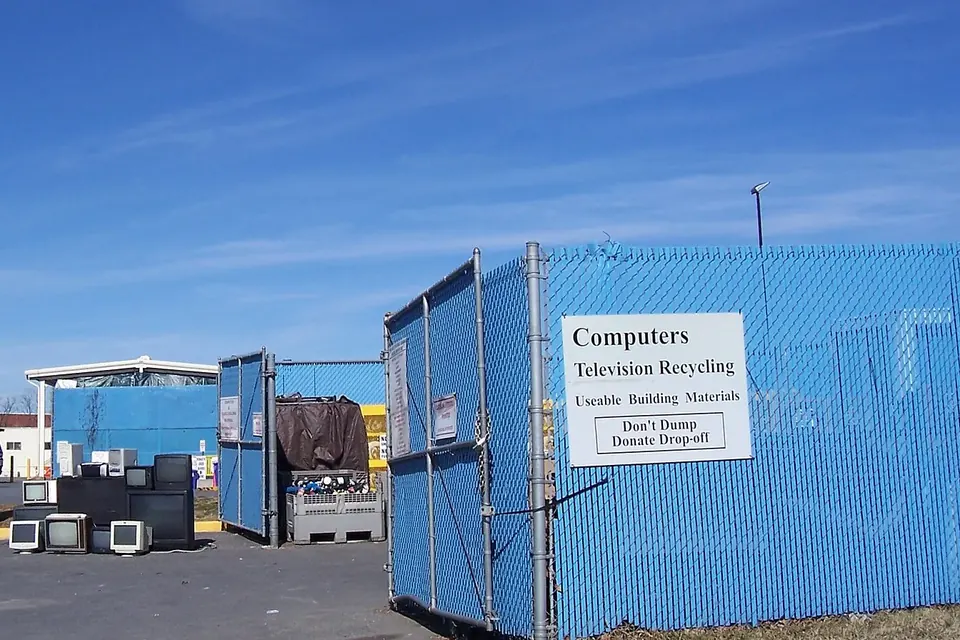 Fenced blue containers at a public drop-off site, with a sign reading Computers, Television Recycling