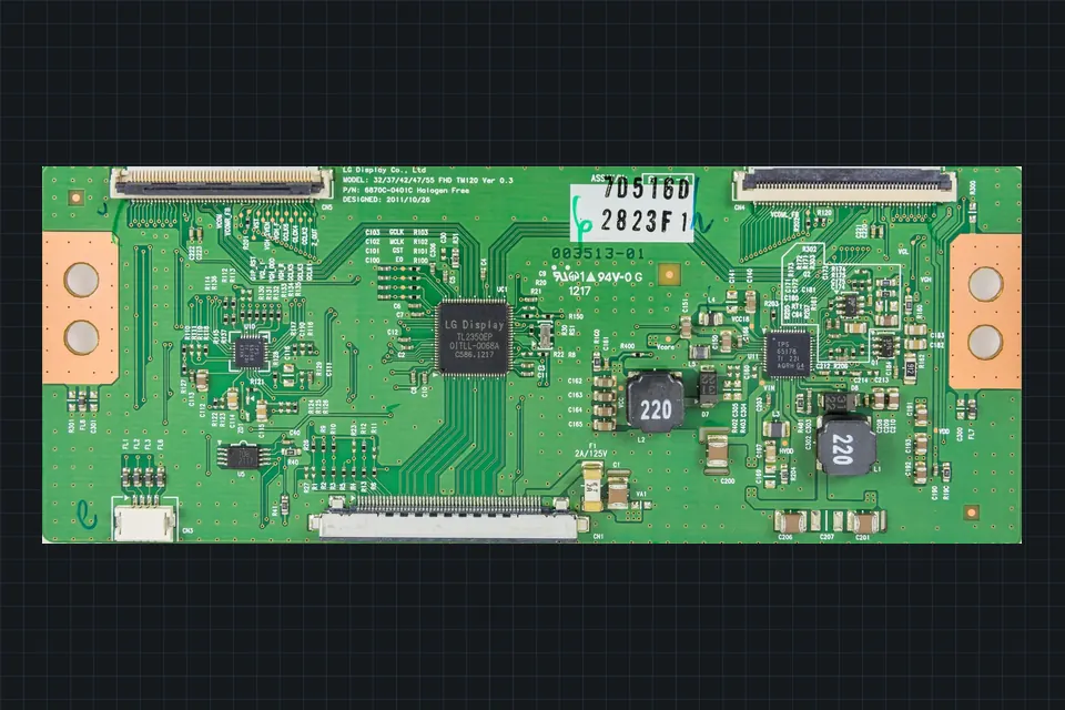 A long, narrow green T-con board with flat-cable connectors along its edges and a part-number sticker