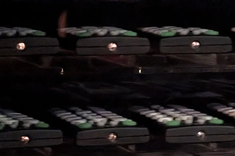Rows of TV remote controls on display, the infrared LED at the tip of each one glowing as a pale dot on camera